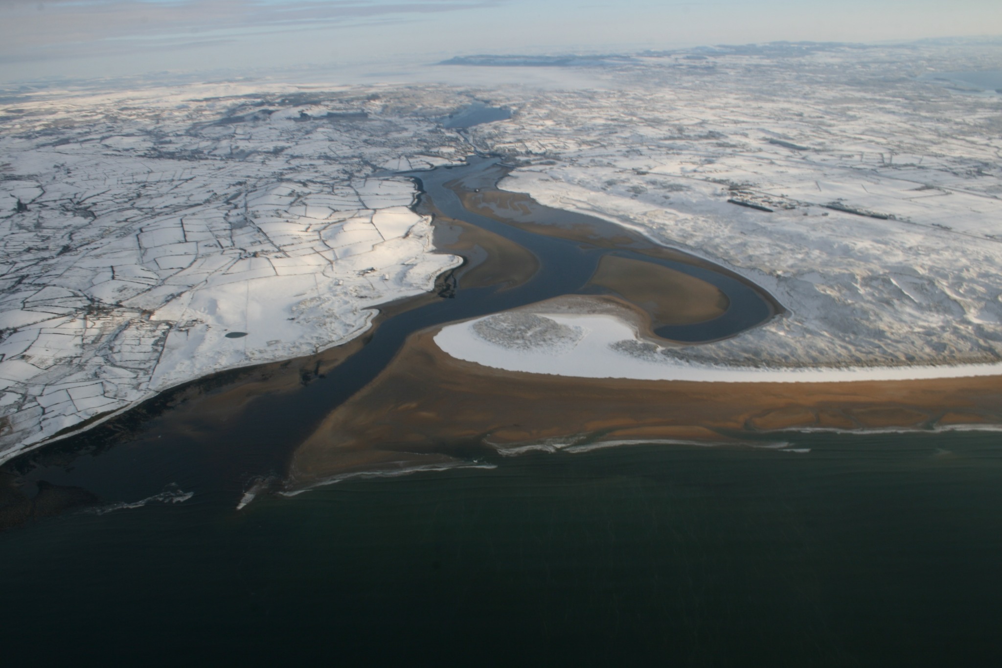 Snow-covered estuary and coastline from above